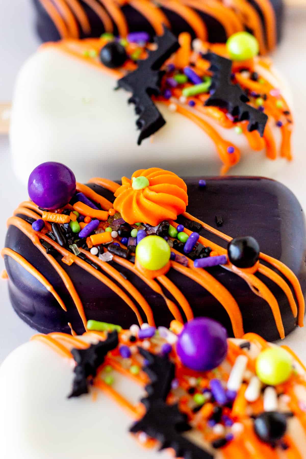 close up view of black cakesicle with Halloween sprinkles and sugar pumpkin