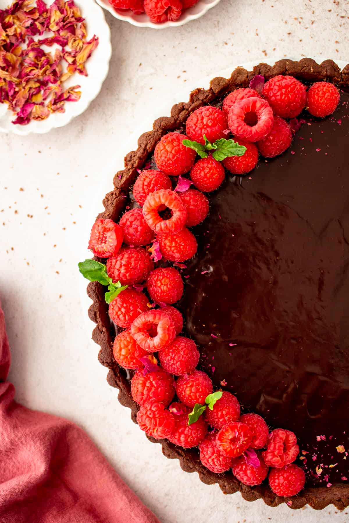 decorated chocolate raspberry tart with raspberries, mint and rose petals