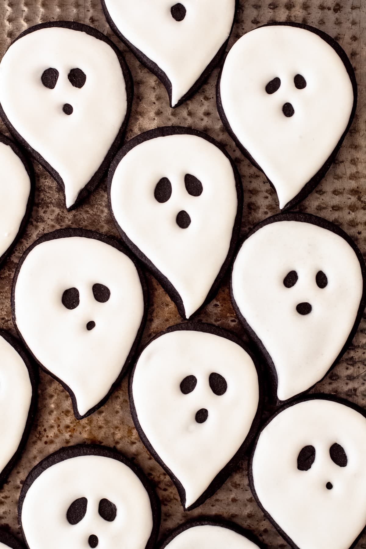 decorated ghost cookies on baking sheet